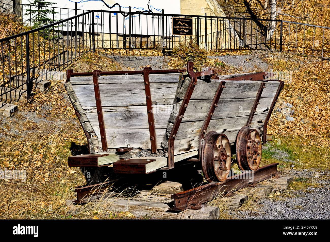 A wooden mining cart from the 1920 aera parked in front of a memorial to the coal mining industry in rural Alberta Canada. Stock Photo