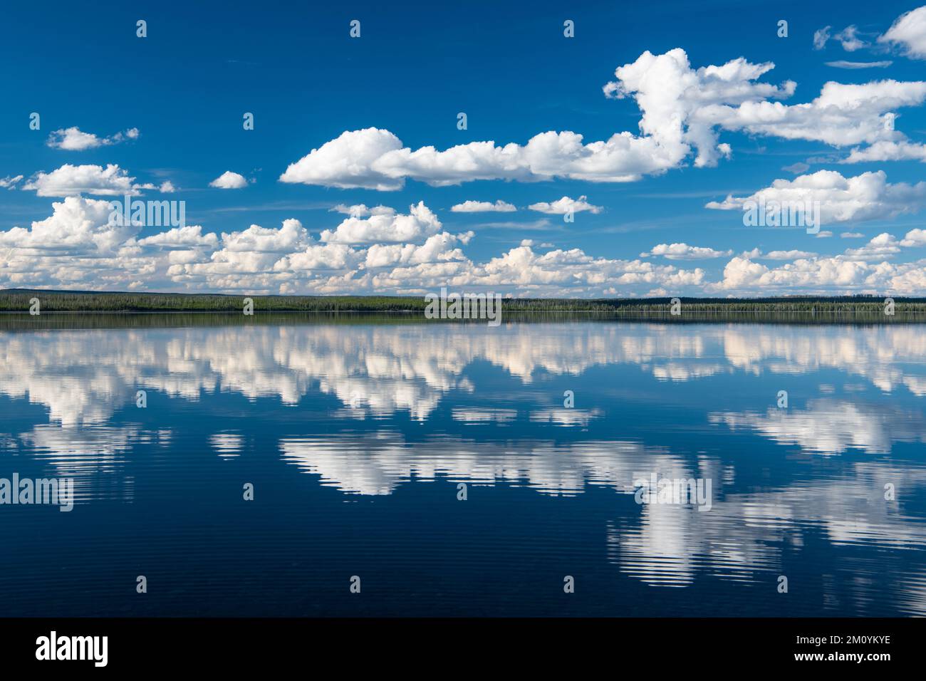 Peaceful, idyllic scene of blue sky and fluffy white clouds reflected ...