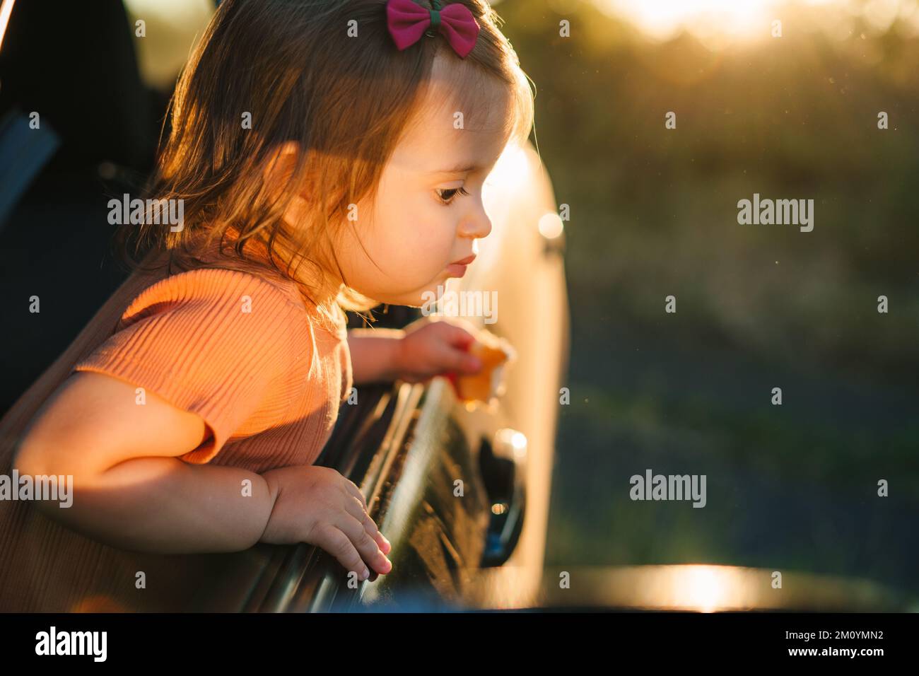 Adorable little girl sticking her head out the car window looking forward for a roadtrip or travel. Happy family. Nature summer. Summer vacation fun Stock Photo
