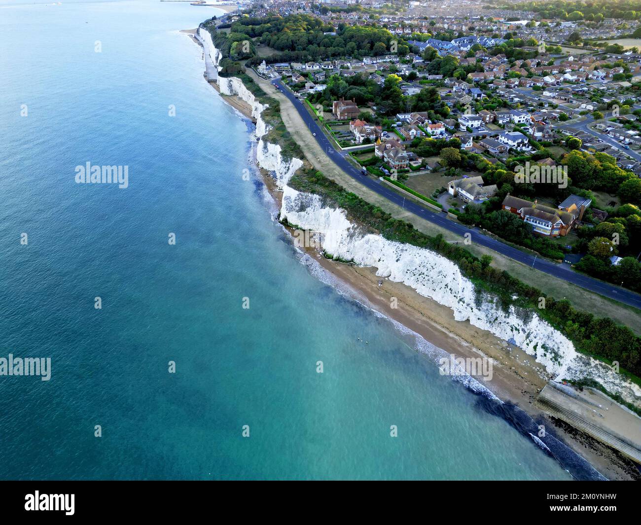 An aerial view of sea waves breaking beach with buildings in