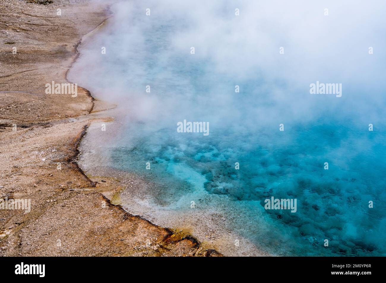 A beautiful pool of clear water and steam forms abstract scene with hues of blue and turquoise at Excelsior Geyser, Yellowstone National Park, Wyoming Stock Photo