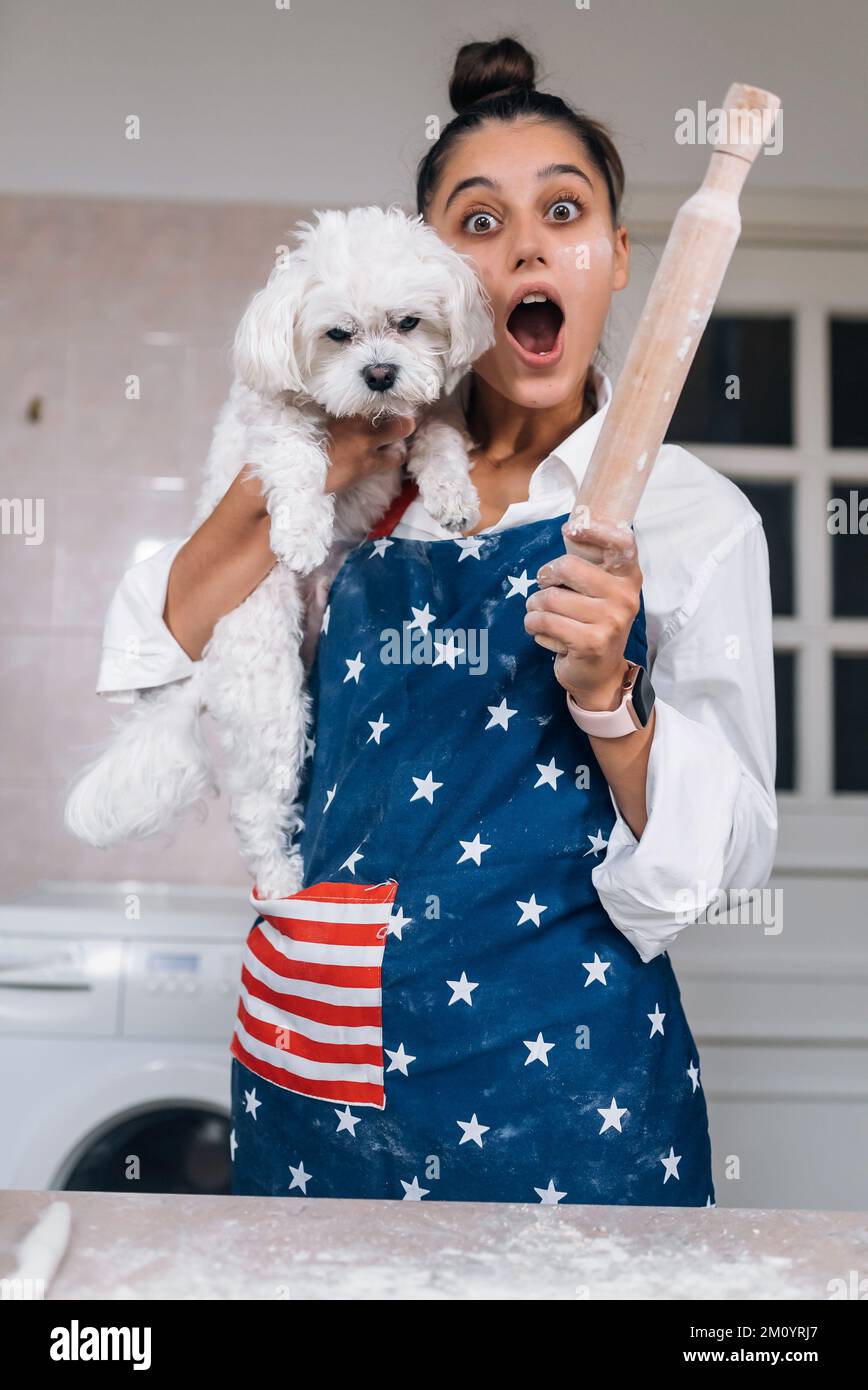 Cheerful woman with a rolling pin and white Maltese dog Stock Photo