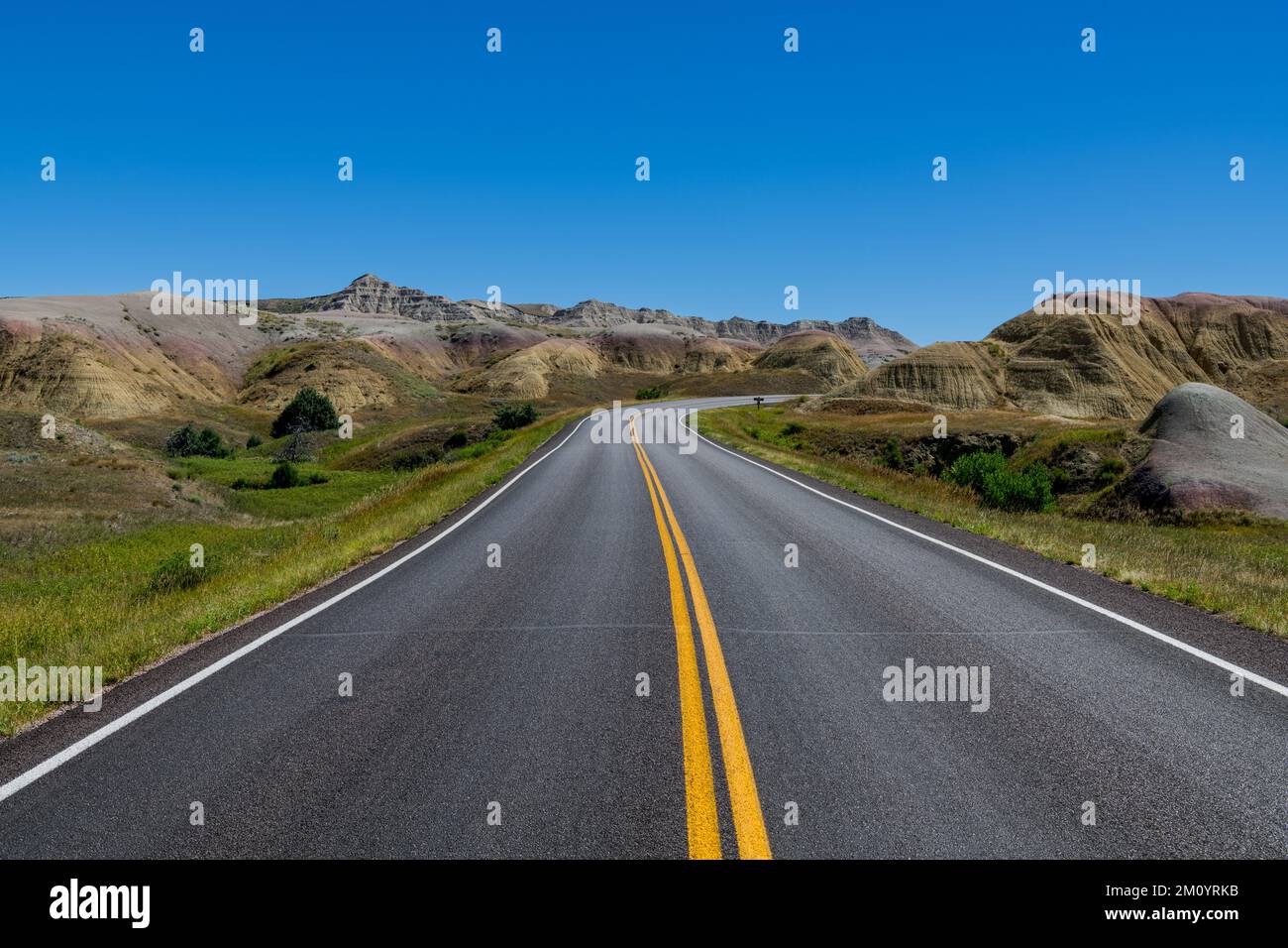 Highway through a landscape of grassy meadows and colorful peaks in Badlands National Park, South Dakota Stock Photo