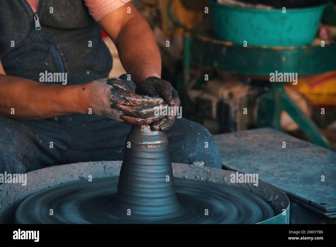 Midsection of professional potter making bowl in pottery