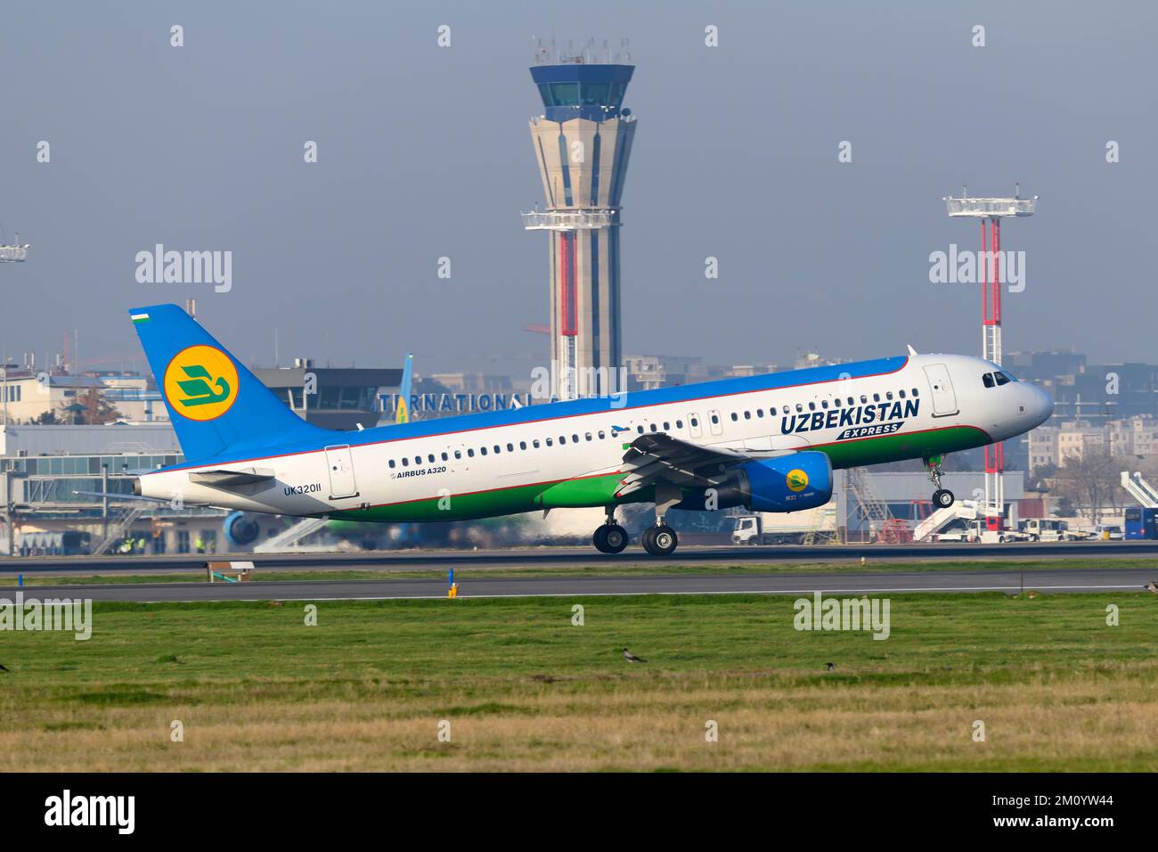 Uzbekistan Airways Express Airbus A320 landing at Tashkent Airport. Aircraft of Uzbekistan Express with Tashkent air traffic control ATC tower behind. Stock Photo