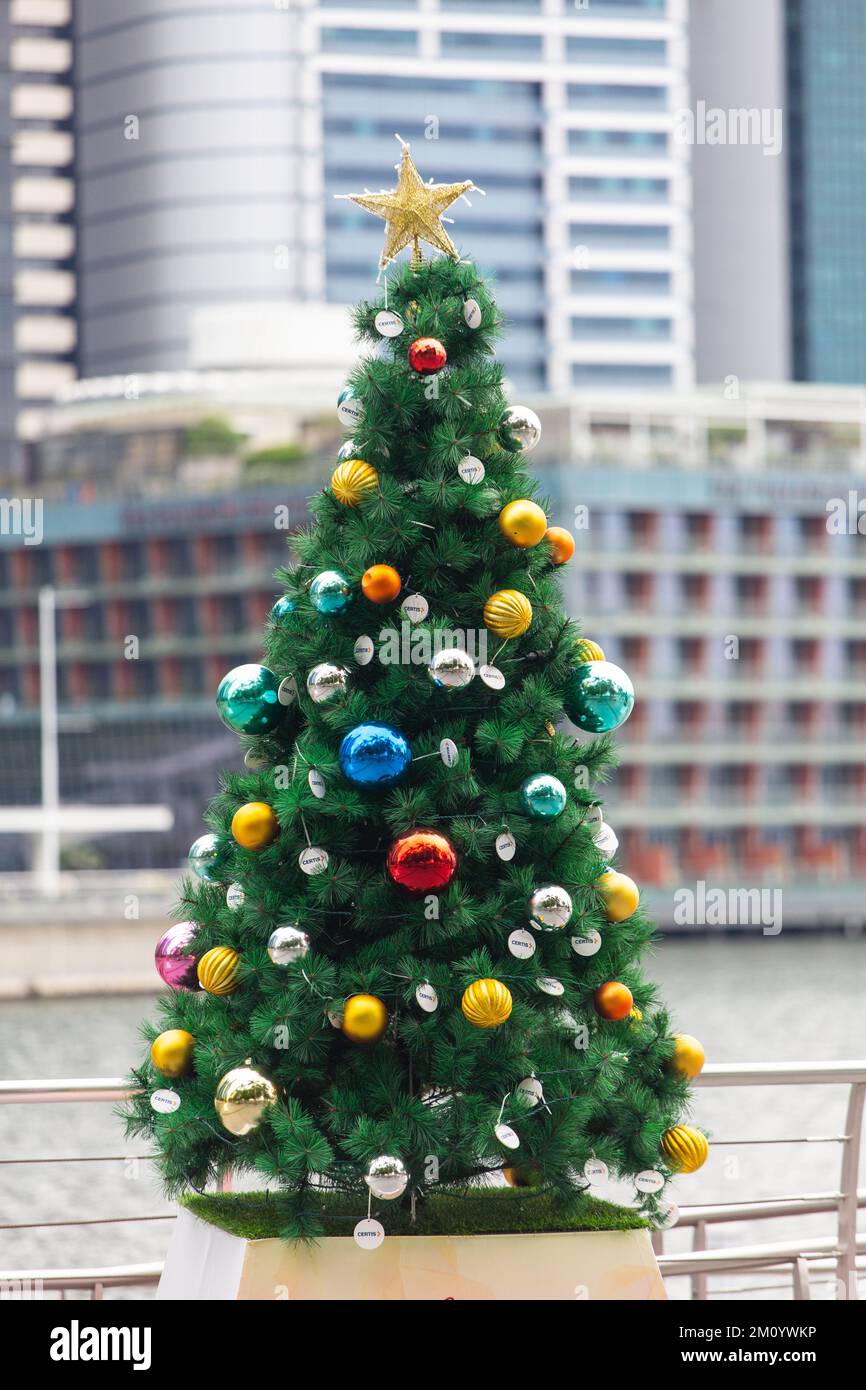 Vertical view of a Christmas tree decoration at outdoor against various buildings as background. Stock Photo