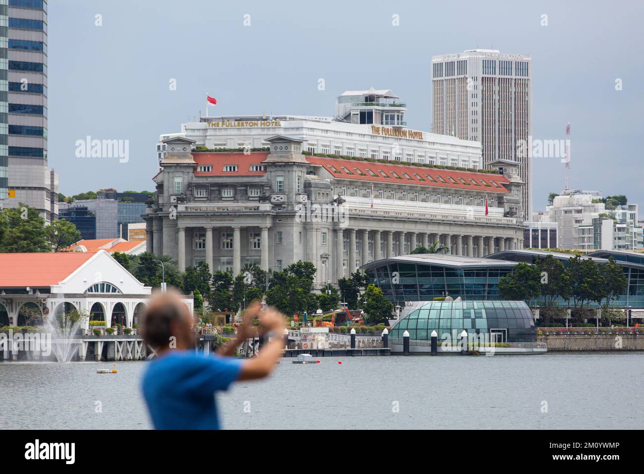 Neoclassical architecture of Fullerton Hotel in Singapore. With a visitor taking picture in the foreground. Stock Photo