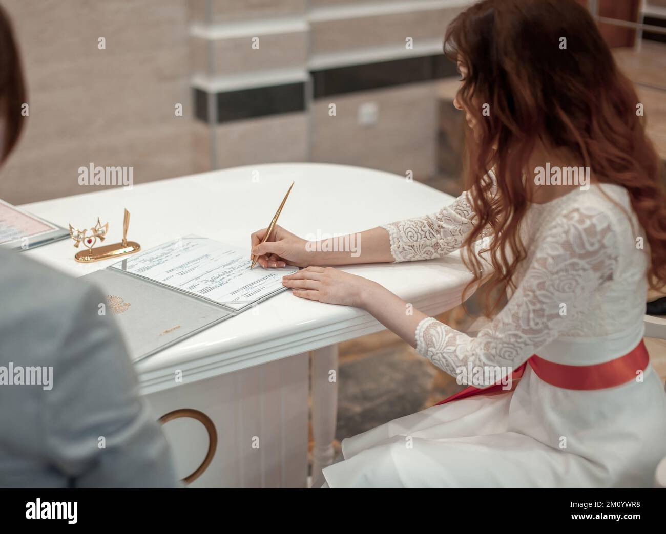 bride signing paper in white dress Stock Photo