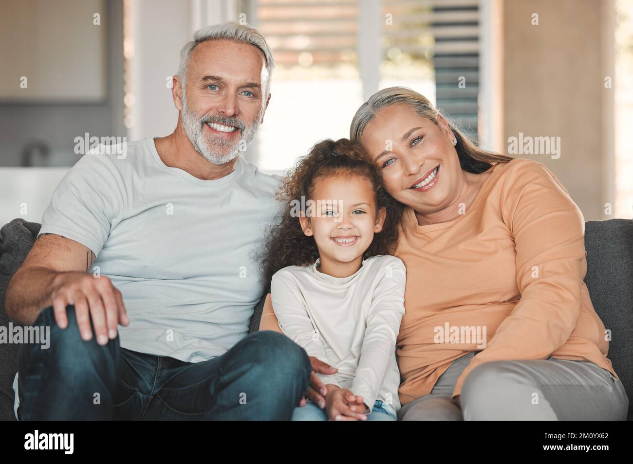 Live your life with love as your guiding principle. a happy senior couple and their granddaughter relaxing on the sofa at home. Stock Photo