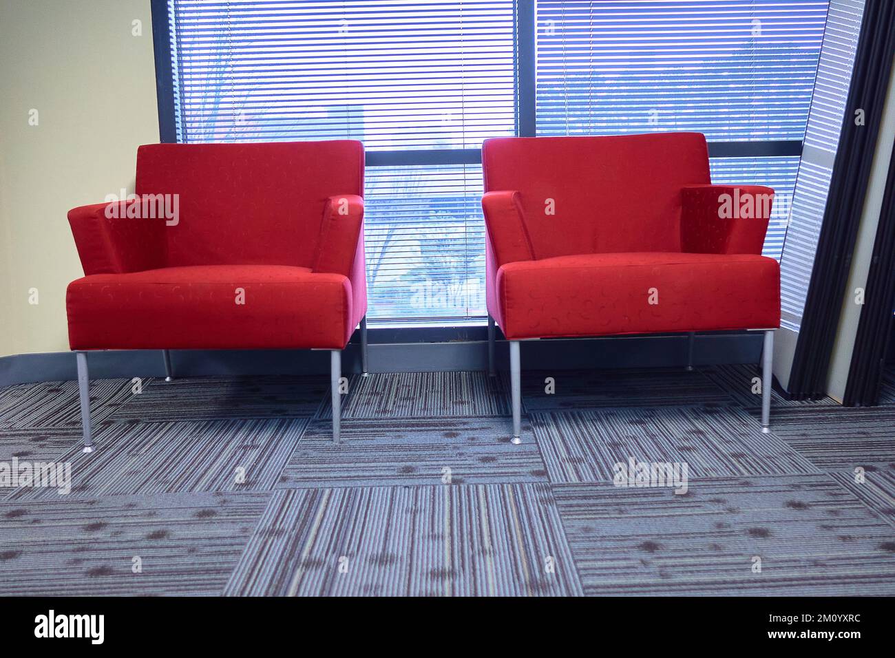 Two red chairs in a office building carpet by a window Stock Photo