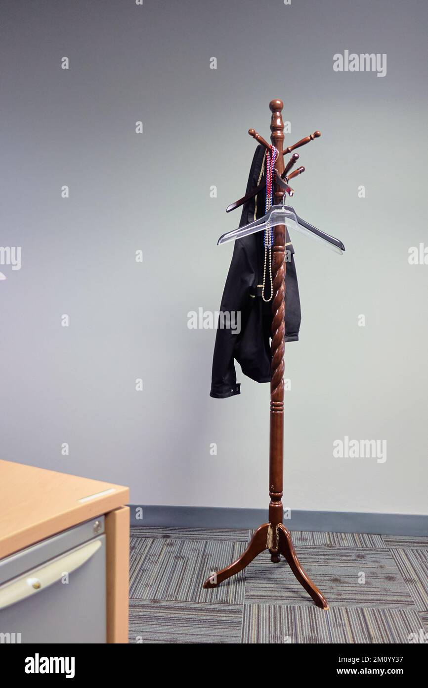 Wood coat rack stand alone with hanger on it in office building Stock