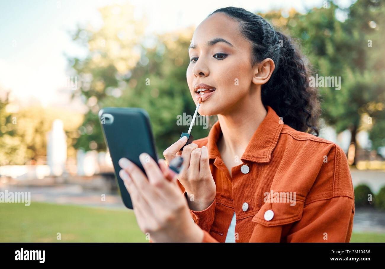 Time for a touch up. a female applying makeup in a park. Stock Photo