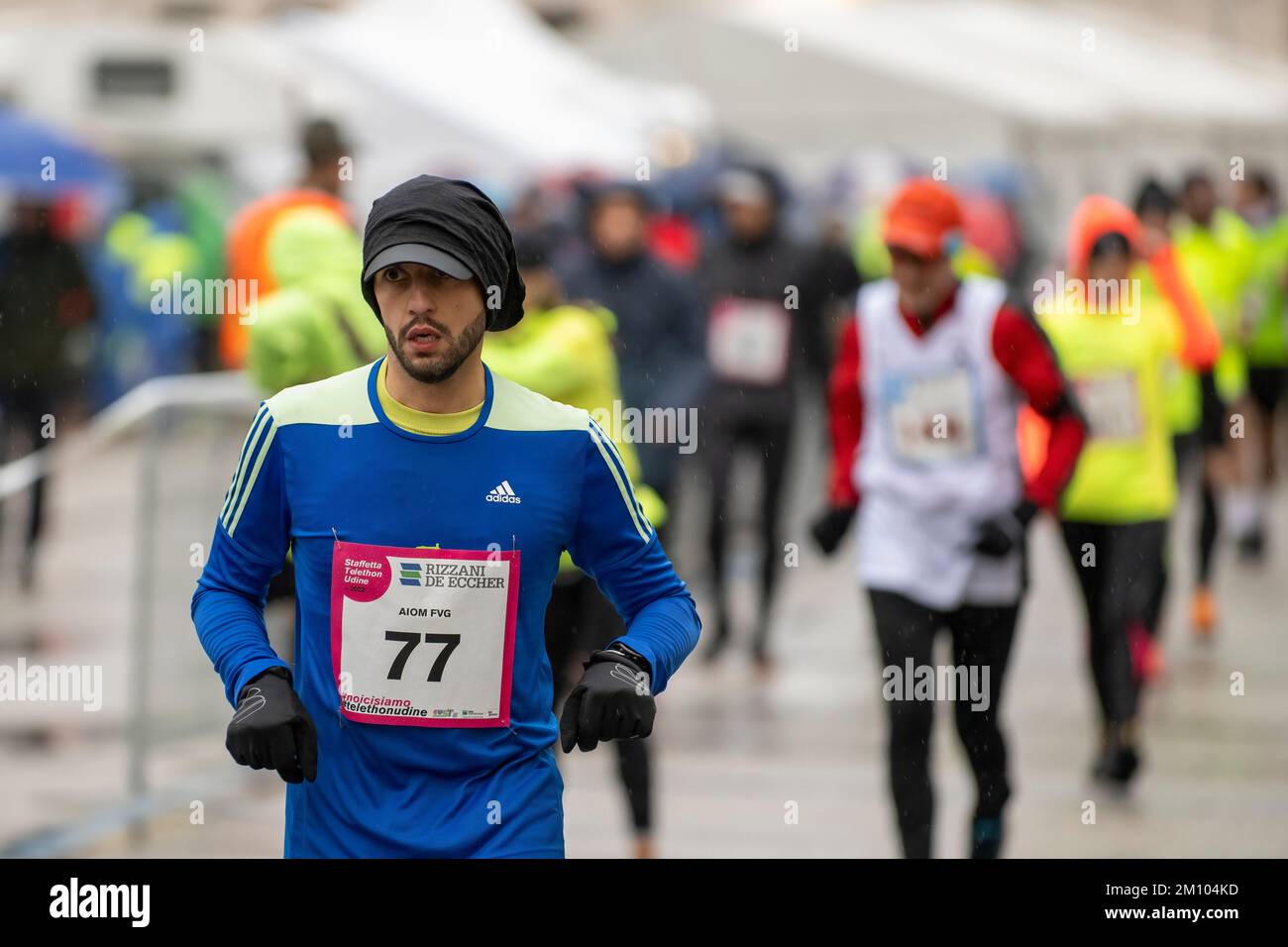 Athletes running under the rain in occasion of the Telethon marathon relay race. Udine city, Italy. December 4, 2022. Stock Photo