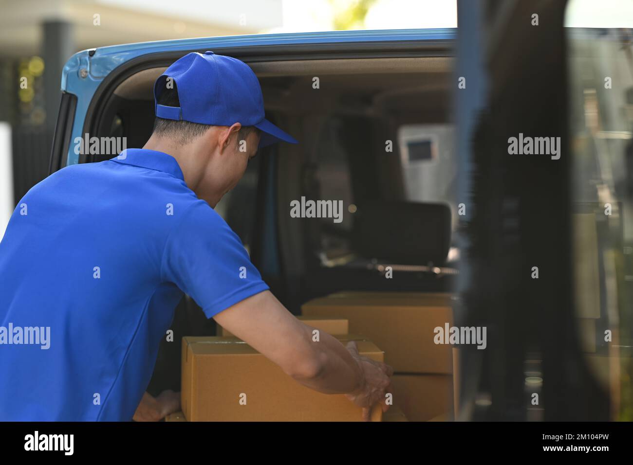 Back view of delivery men unloading cardboard boxes from cargo van