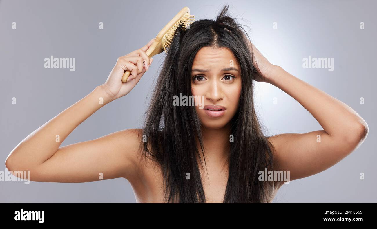 Its a knotty situation. Studio shot of a young woman with damaged hair posing against a grey background. Stock Photo