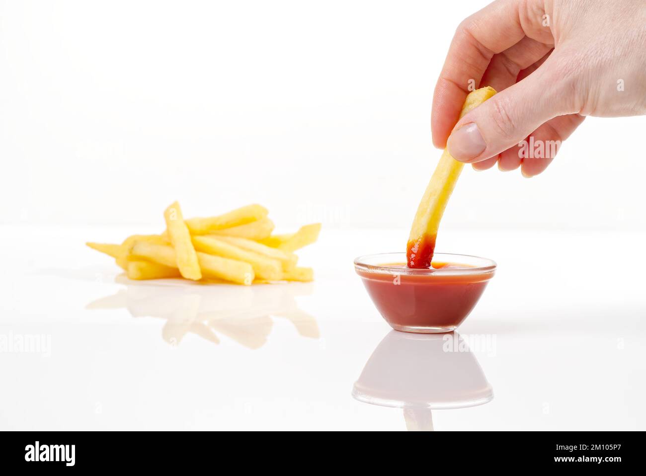 Hand dip french fries chips into ketchup isolated on white background