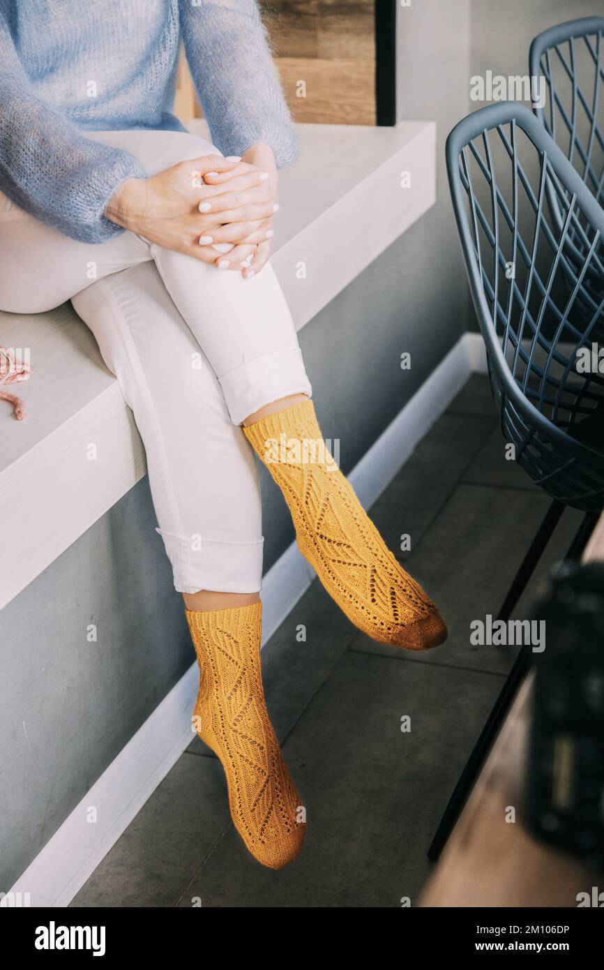 Comforting cozy woman in knitted woolen winter yellow socks, whi Stock Photo
