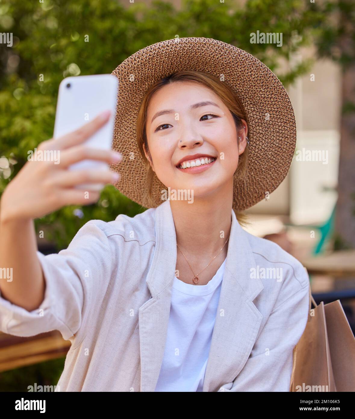Selfie, smartphone and shopping bag of woman in city or park for social media post, profile picture update and fashion blog in Japan. Cellphone Stock Photo