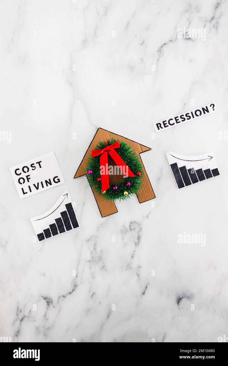 graphs with cost of living going up economic growth going down due to recession next to cardboard house with festive wreath, concept of post pandemic Stock Photo