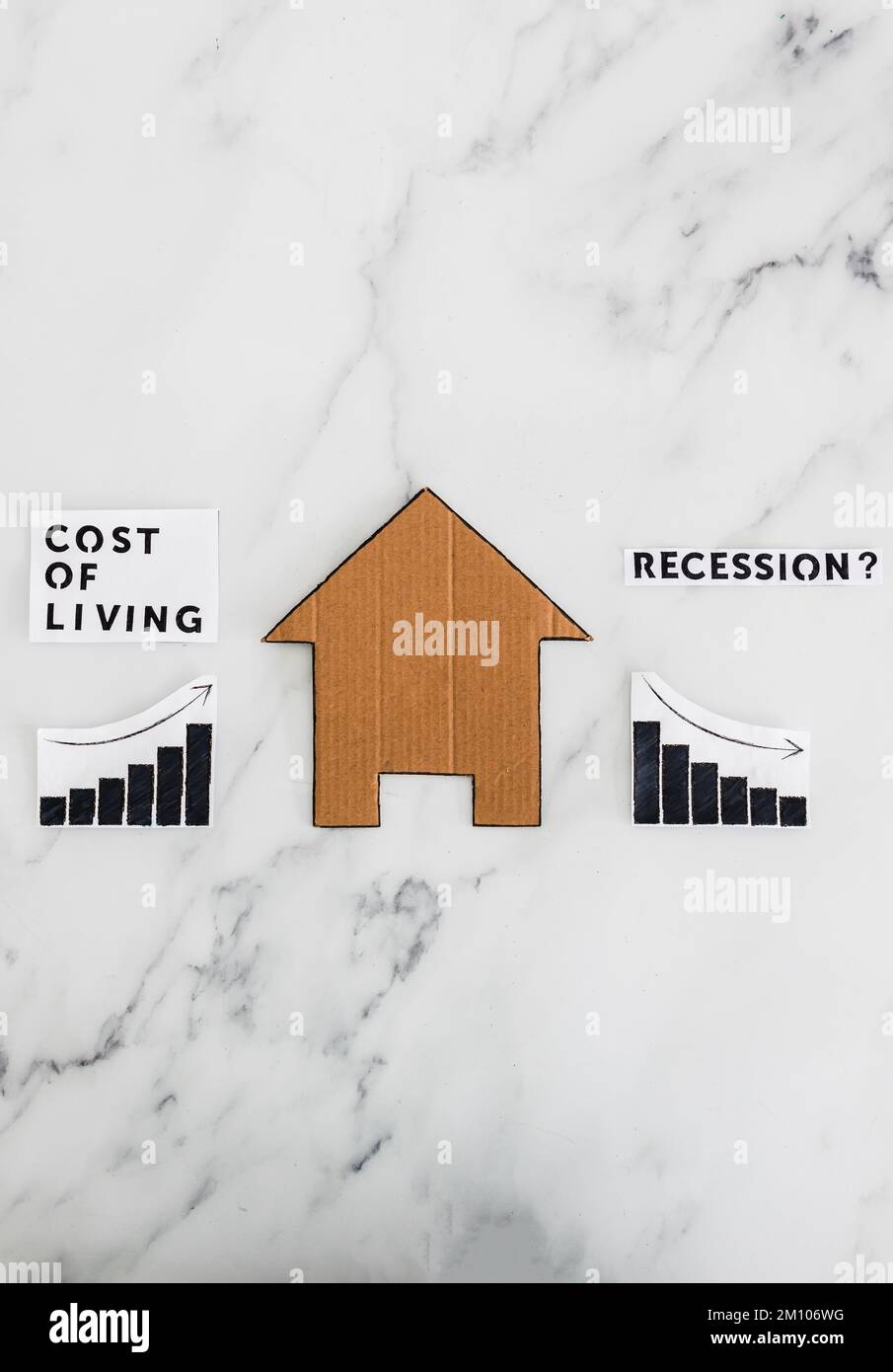 graphs with cost of living going up and economic growth going down due to recession next to cardboard house, concept of post pandemic economy during w Stock Photo