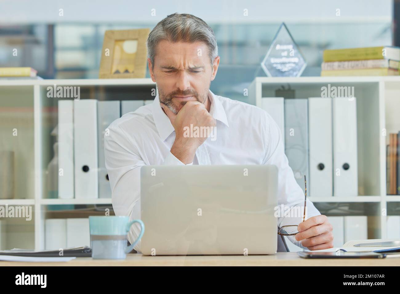 Businessman, laptop and thinking and confused in office for 404 error, internet glitch or financial report concern. Technology problem, reading Stock Photo