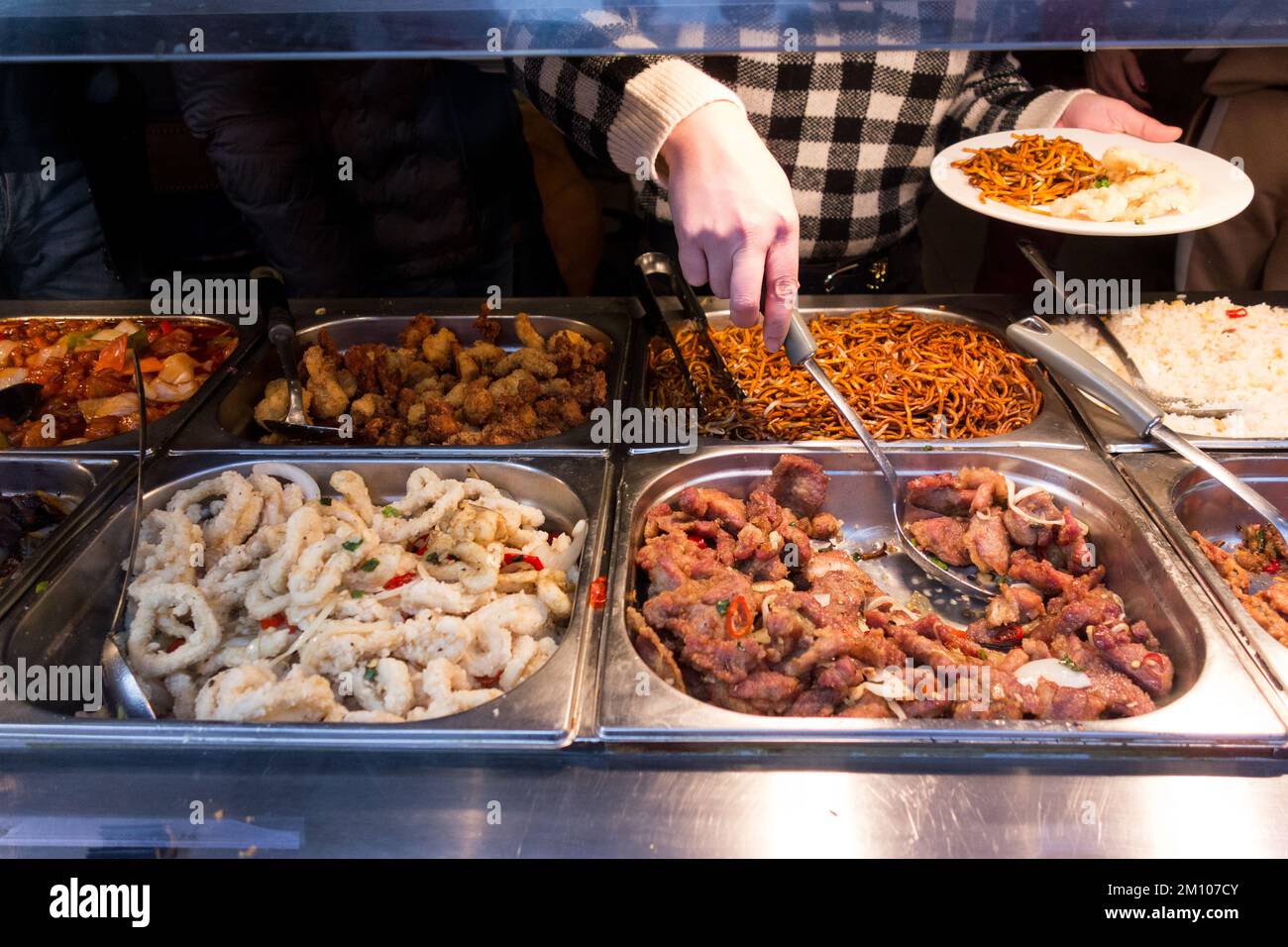 A customer with a platefull of noodles in a selfservice Chinese