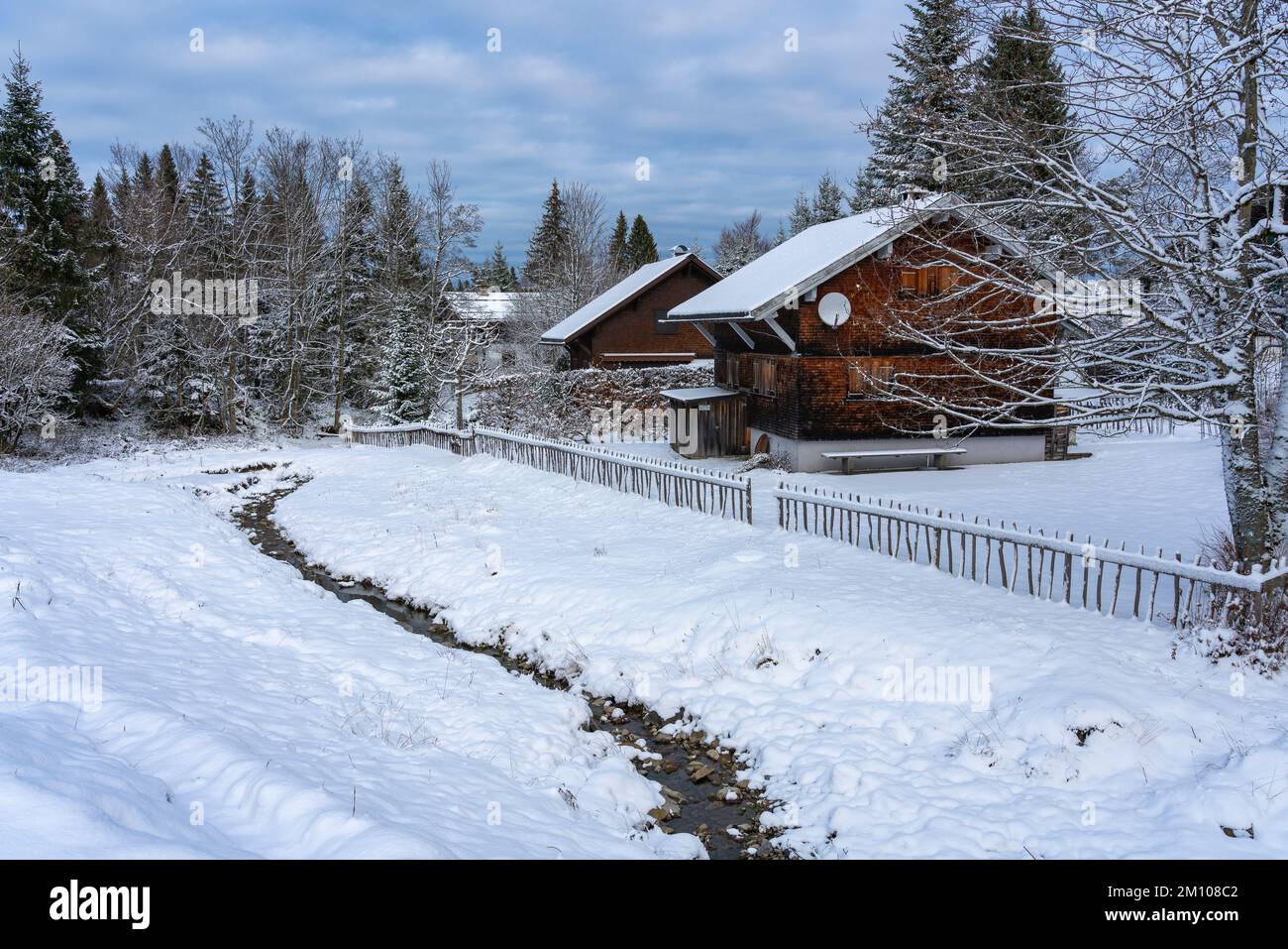 Holzhaus, Ferienhaus am Waldrand auf dem Hügel im ersten Schnee, verschneite Landschaft mit weißen Wiesen und Bäumen. Advent und Weihnachtszeit Ferien Stock Photo
