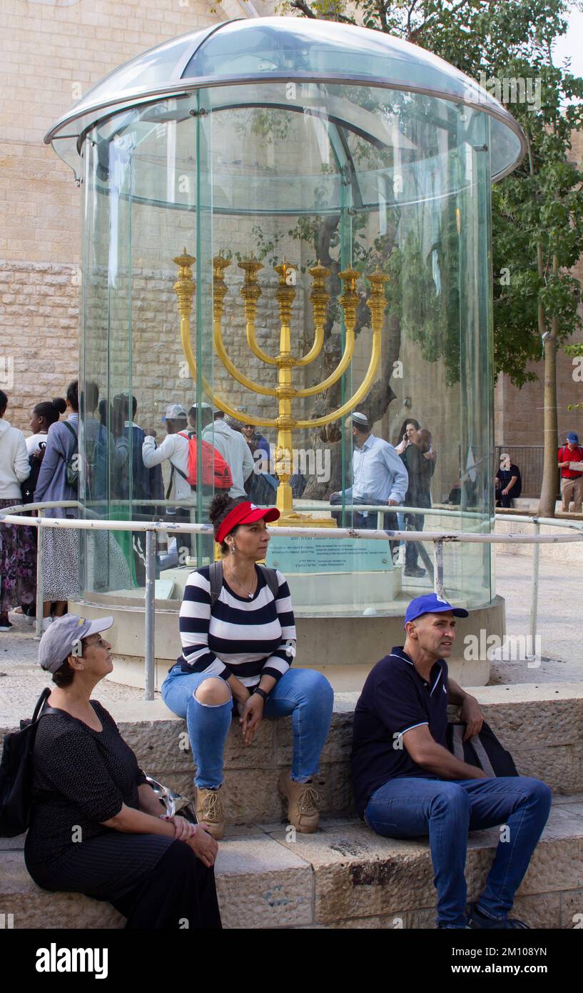 9 Nov 2022 The solid gold menorah secured in a bullet proof case on display in the cobbled square of the Jewish Quarter in Jerusalem. Visitors rest on Stock Photo