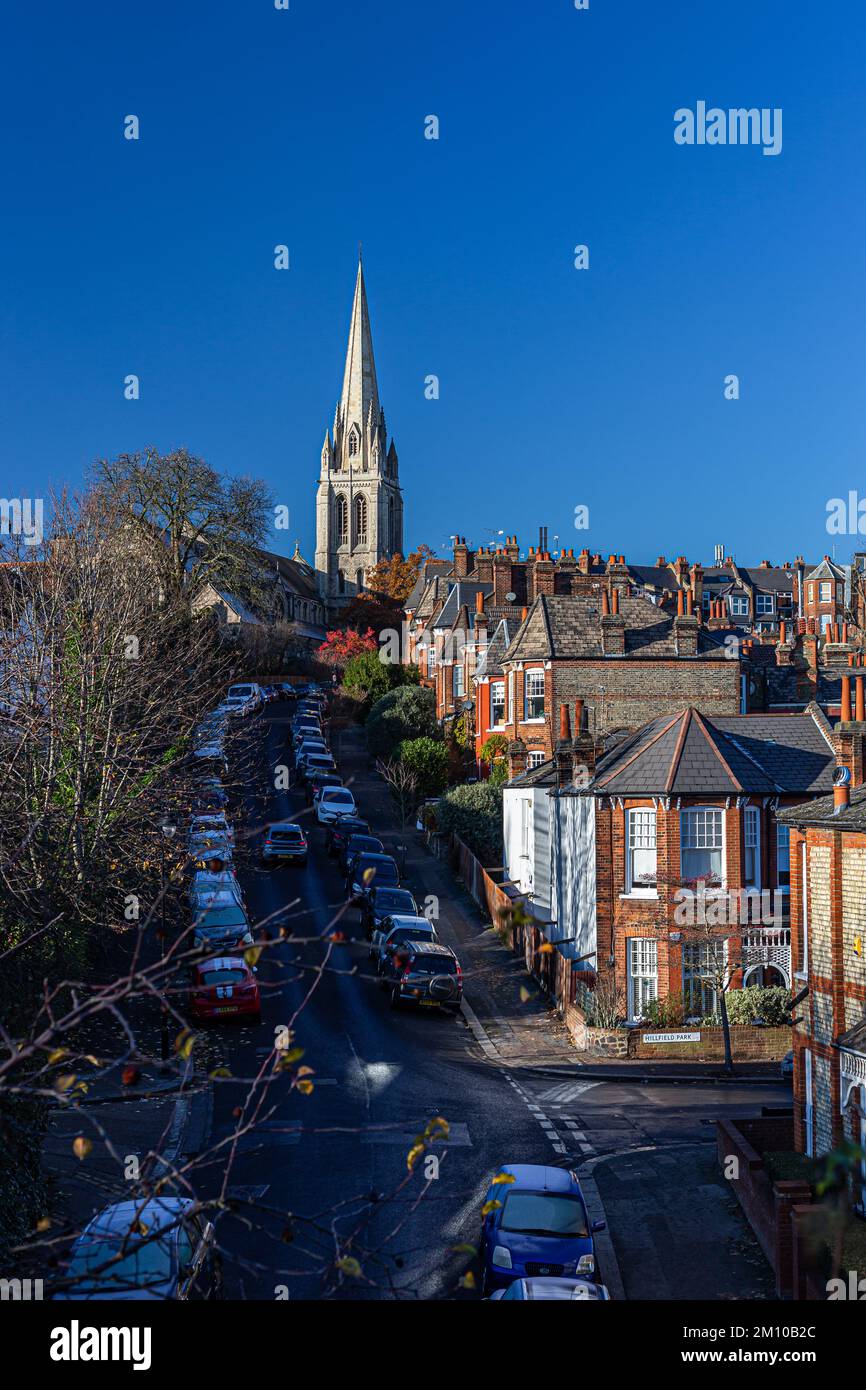 Looking over muswell hill from up high.A church spire against a deep blue sky as well as many roofs and chimneys of terraced houses.Many cars parked Stock Photo