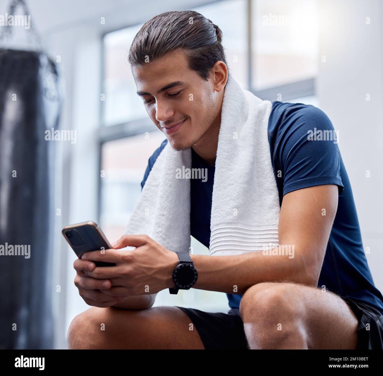 Fitness, phone and man relax in gym tracking workout, exercise or progress on app. Tech, sports and happy male with towel and mobile smartphone for Stock Photo