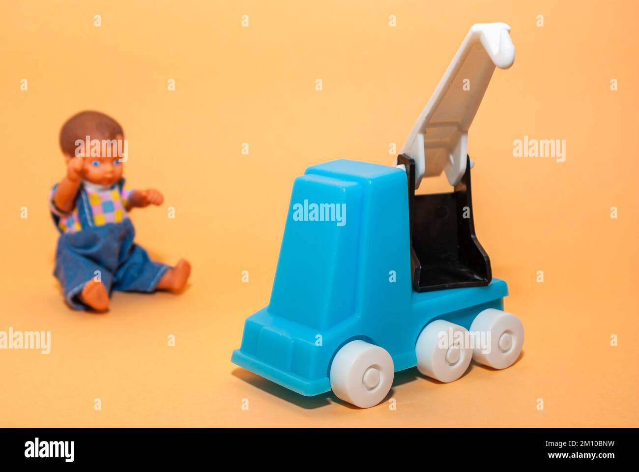 In front of a beige background, a mobile crane and a boy doll, the concept of childhood play and the construction industry. Stock Photo