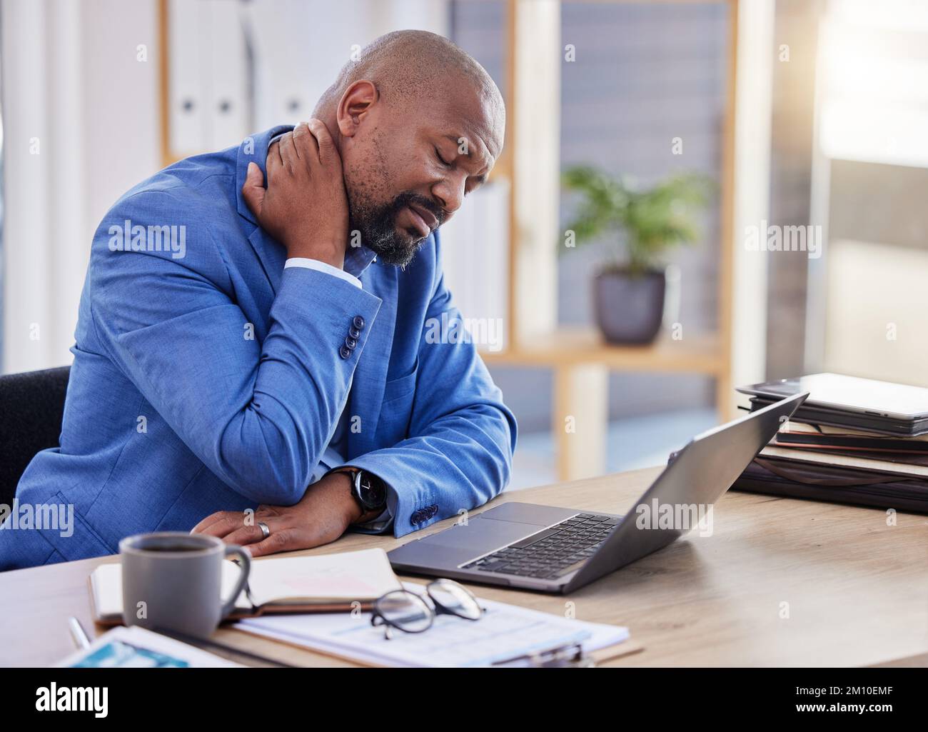 Black man , stress and tired burnout with neck pain in the office due to bad posture and uncomfortable chair. Fatigue, problem or frustrated worker Stock Photo