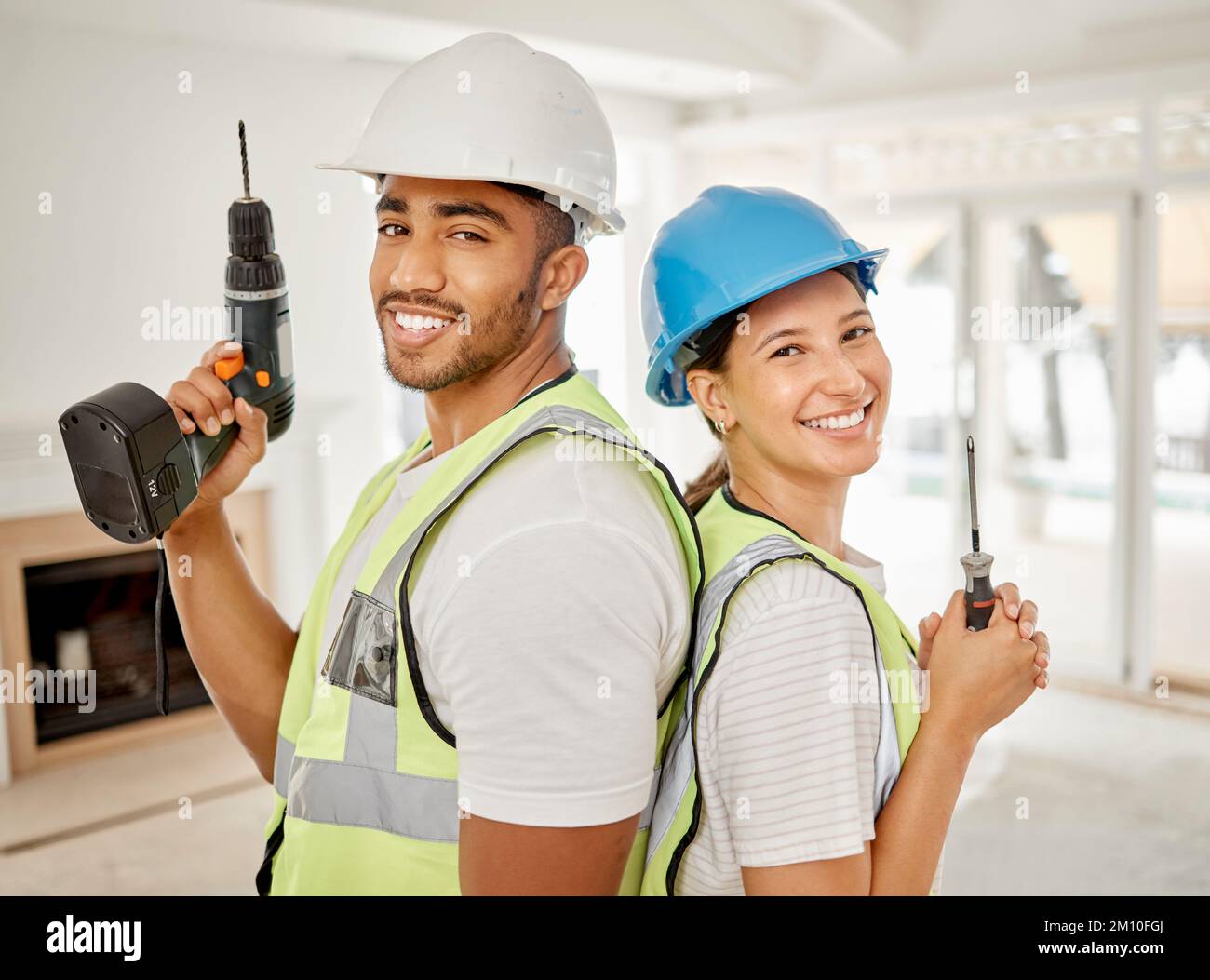 Time to make this house a home. two construction workers standing back to back in a house and holding maintenance equipment. Stock Photo