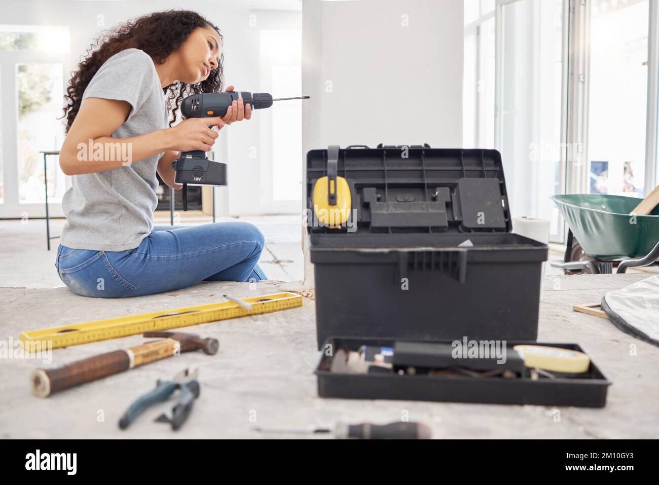 I like to keep busy in my spare time. a woman using a cordless drill while busy renovating. Stock Photo