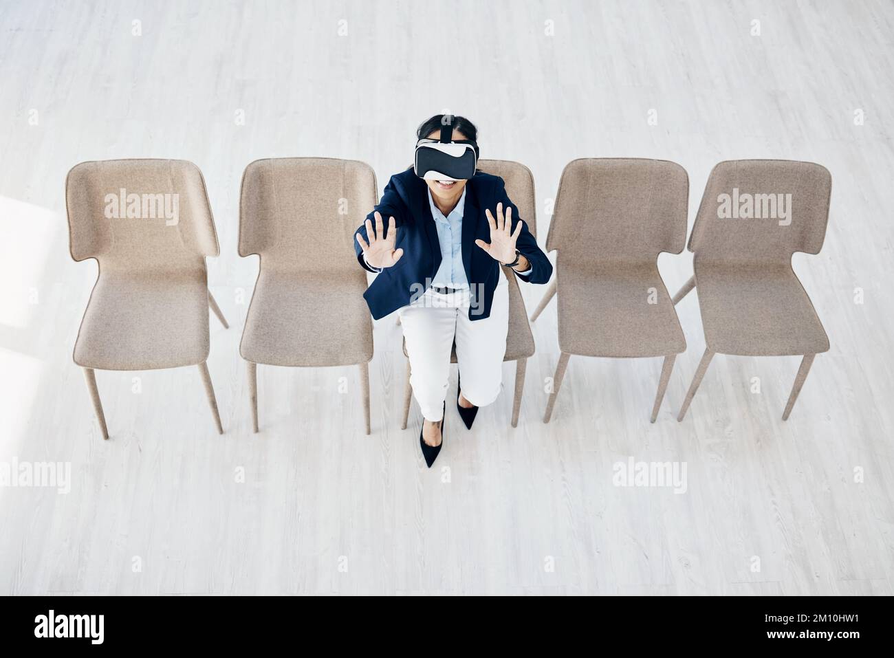 Revolutionising learning in the corporate world. High angle shot of a young businesswoman wearing a VR headset while sitting in line in an office. Stock Photo