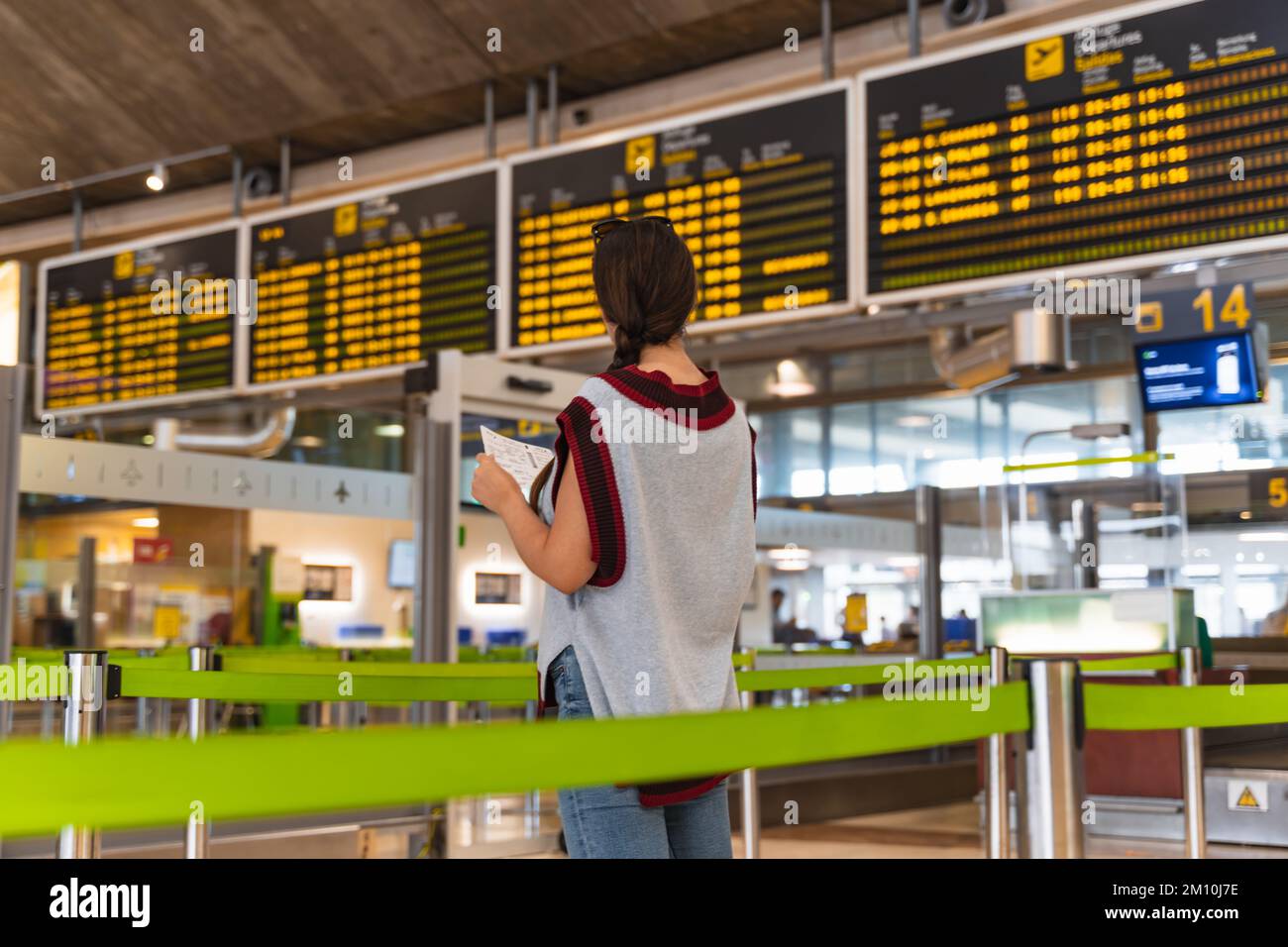 brunette girl with braid at the airport looking at the flight board Stock Photo