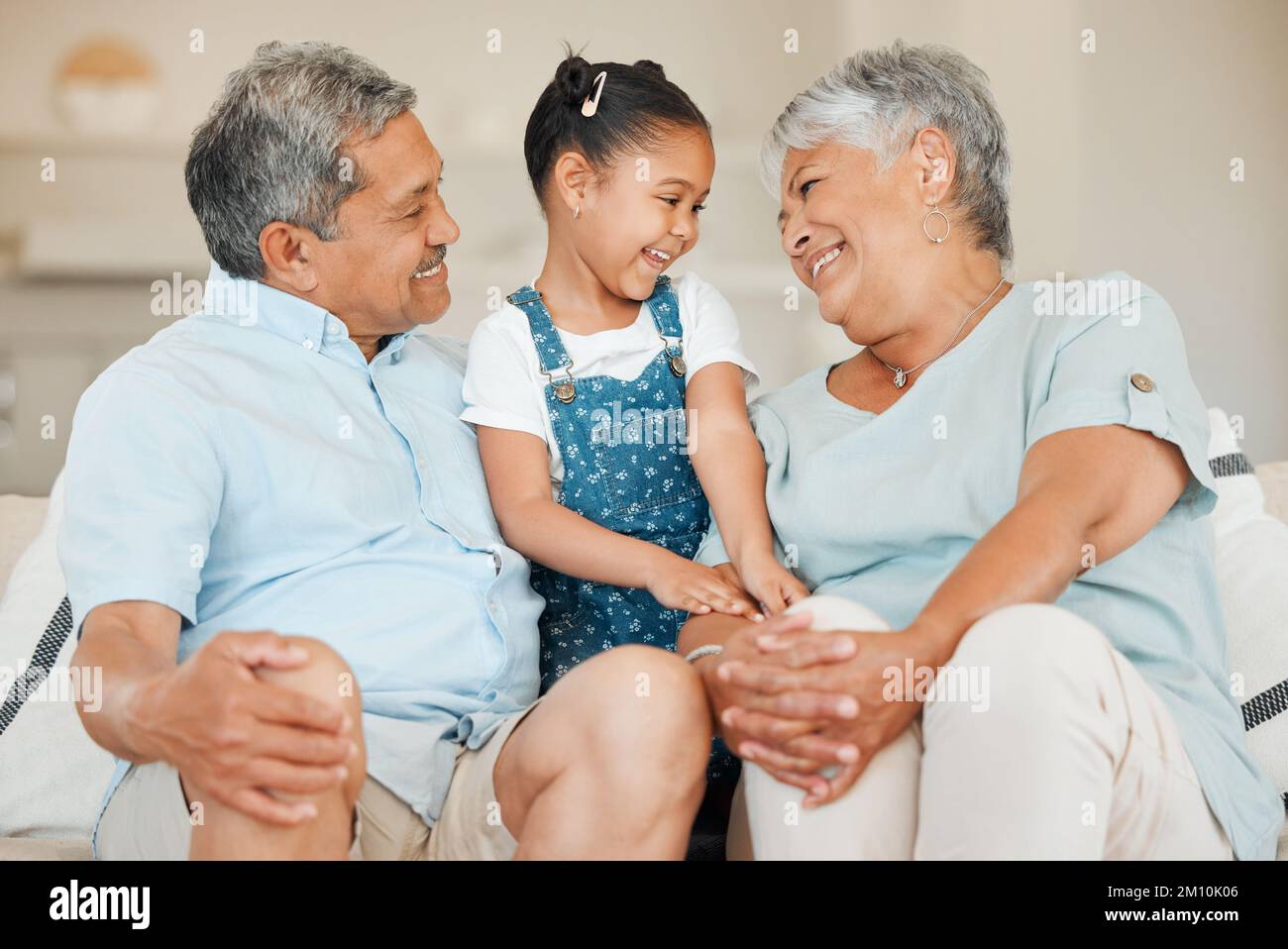 Hold on to your family and friends. grandparents bonding with their granddaughter on a sofa at home. Stock Photo