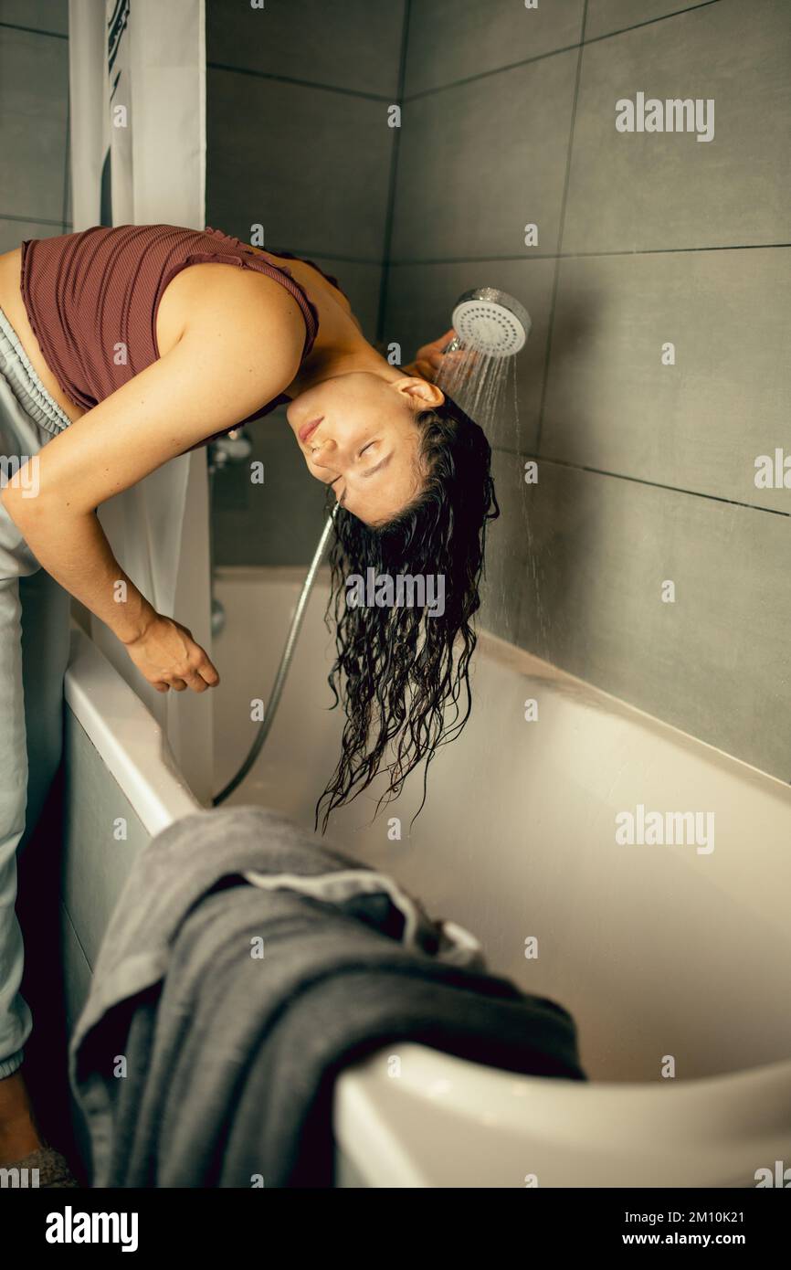 Young woman is washing her hair standing up Stock Photo