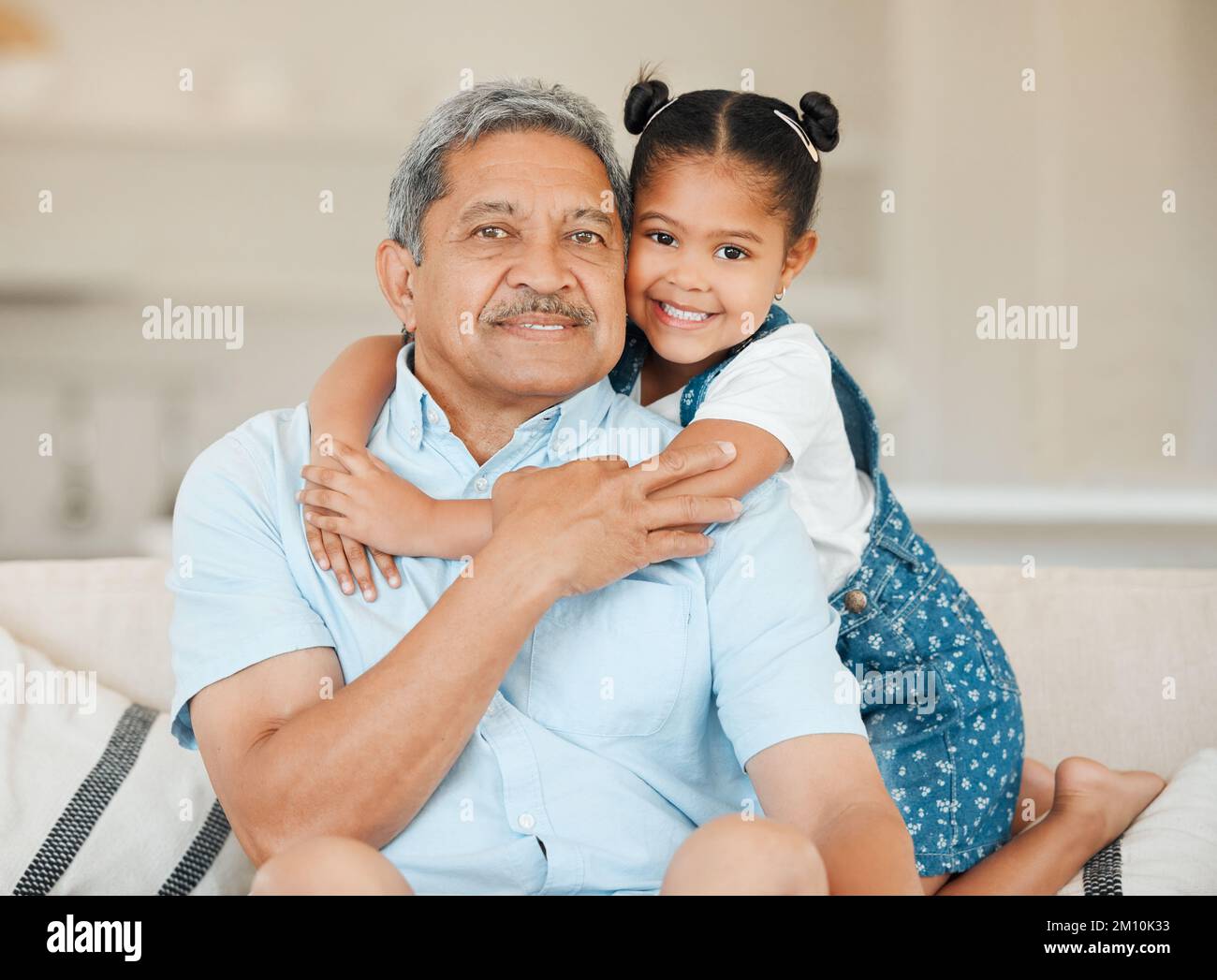 There is no doubt that it is around the family. a grandfather and granddaughter bonding on the sofa at home. Stock Photo