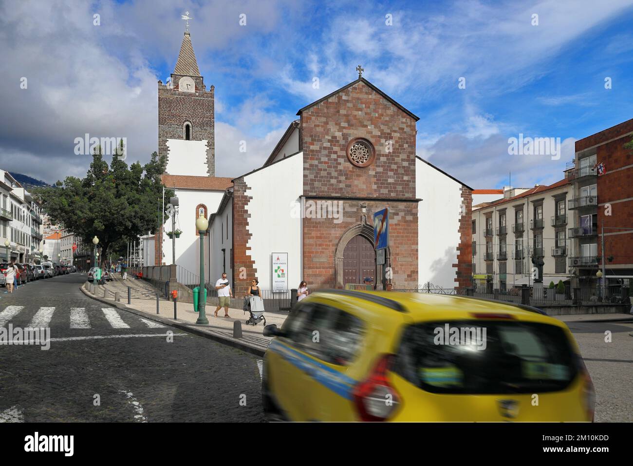 The Cathedral of Our Lady of the Assumption in Sé, Funchal, Madeira, Portugal with taxi driving past in the foreground Stock Photo