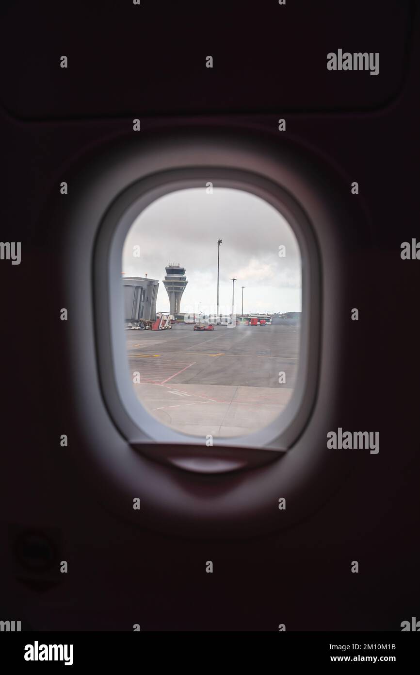 views from the plane overlooking the runway with its boarding bridge and control tower. It is a very gray day. Stock Photo