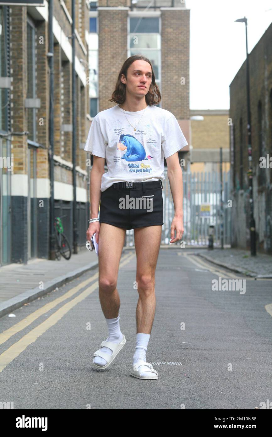 Cool retro vintage style man  with long hair, shorts, print white t shirt, white socks and white sneakers trainers street style Stock Photo