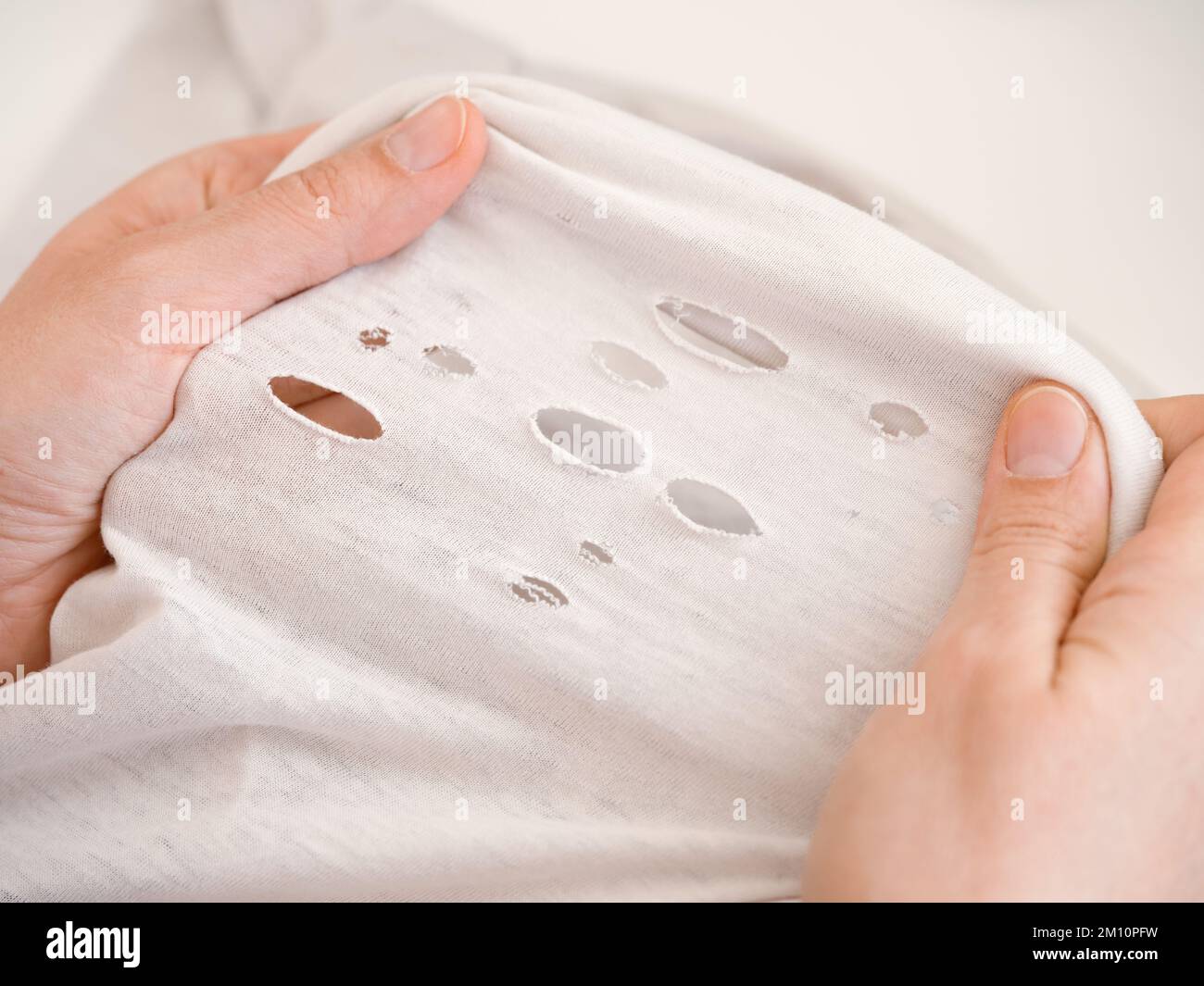 A woman stretching a shirt with holes. Close up. Stock Photo