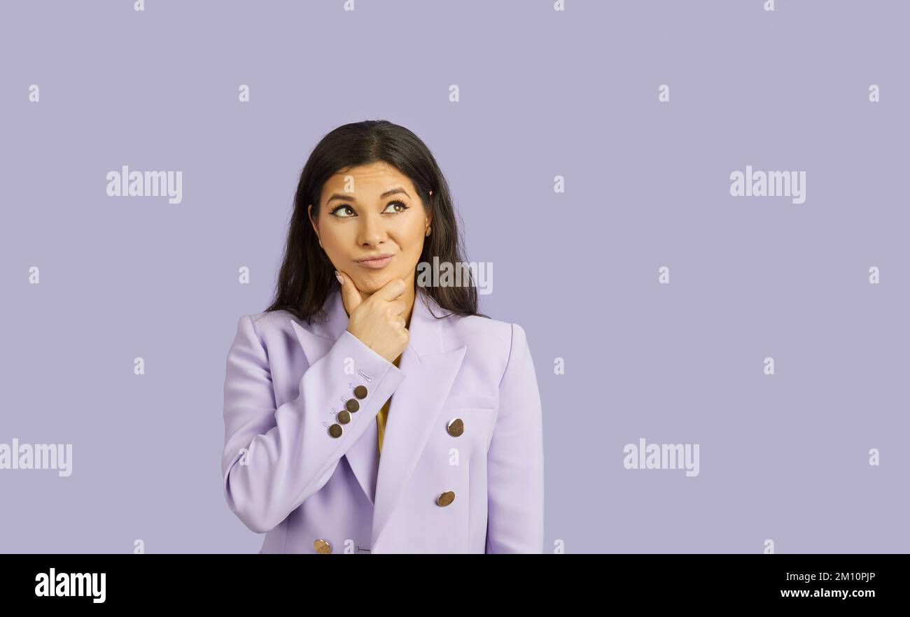 Portrait of beautiful woman with doubtful facial expression isolated on pastel purple background. Stock Photo