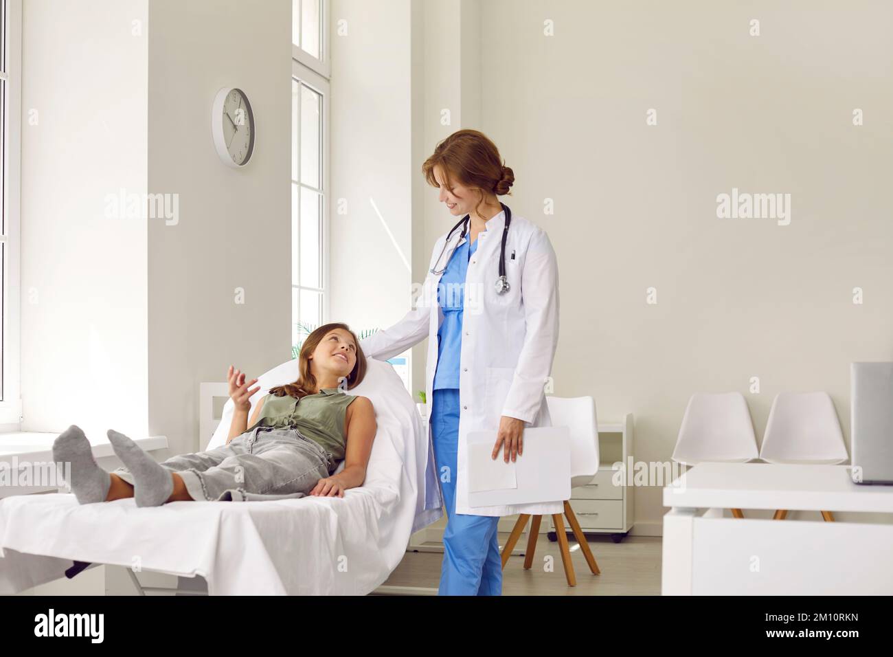 Happy child having medical checkup, lying on examination couch and talking to doctor Stock Photo
