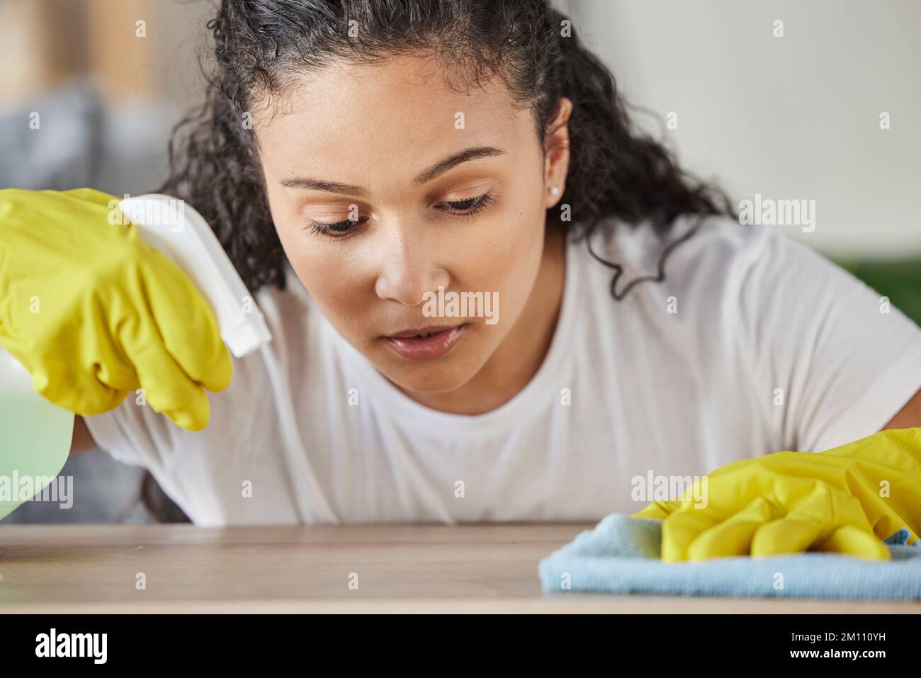 Home, housework and woman with spray bottle cleaning table or counter with detergent in living room. House, maintenance and girl in clean fresh house Stock Photo