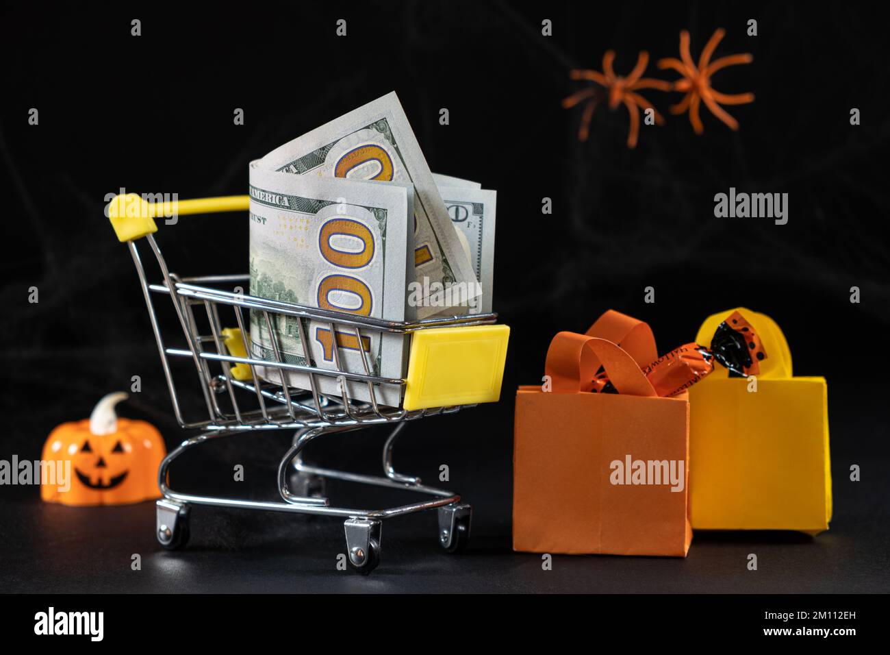 Cart with money hundred-dollar bills, paper bags for purchases. Halloween Sale Stock Photo