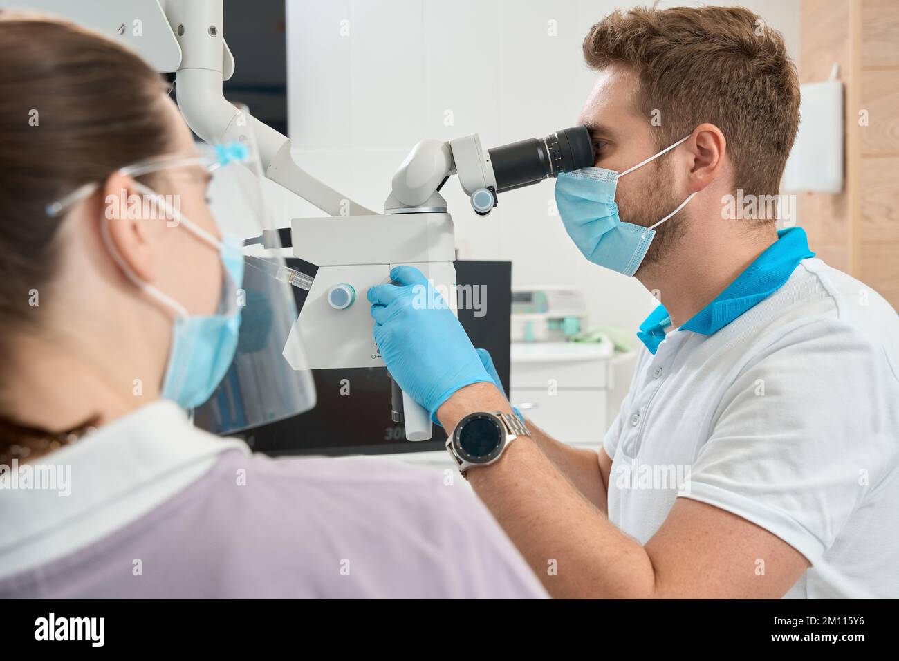 Qualified dentist adjusting modern optical instrument for work Stock