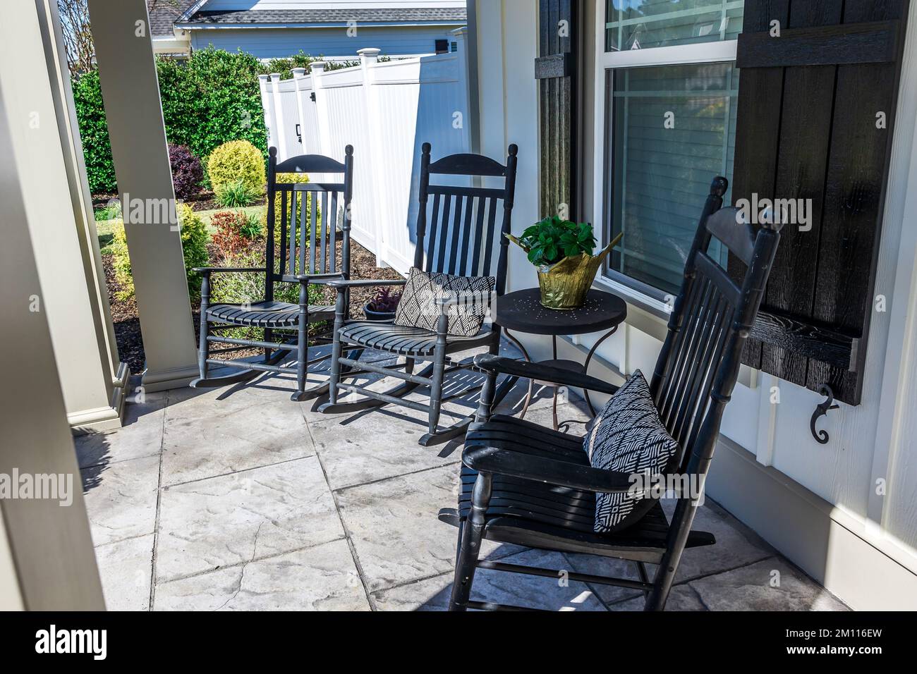 A stamped concrete gray front porch with black rocking chairs sitting in the front for curb appeal Stock Photo