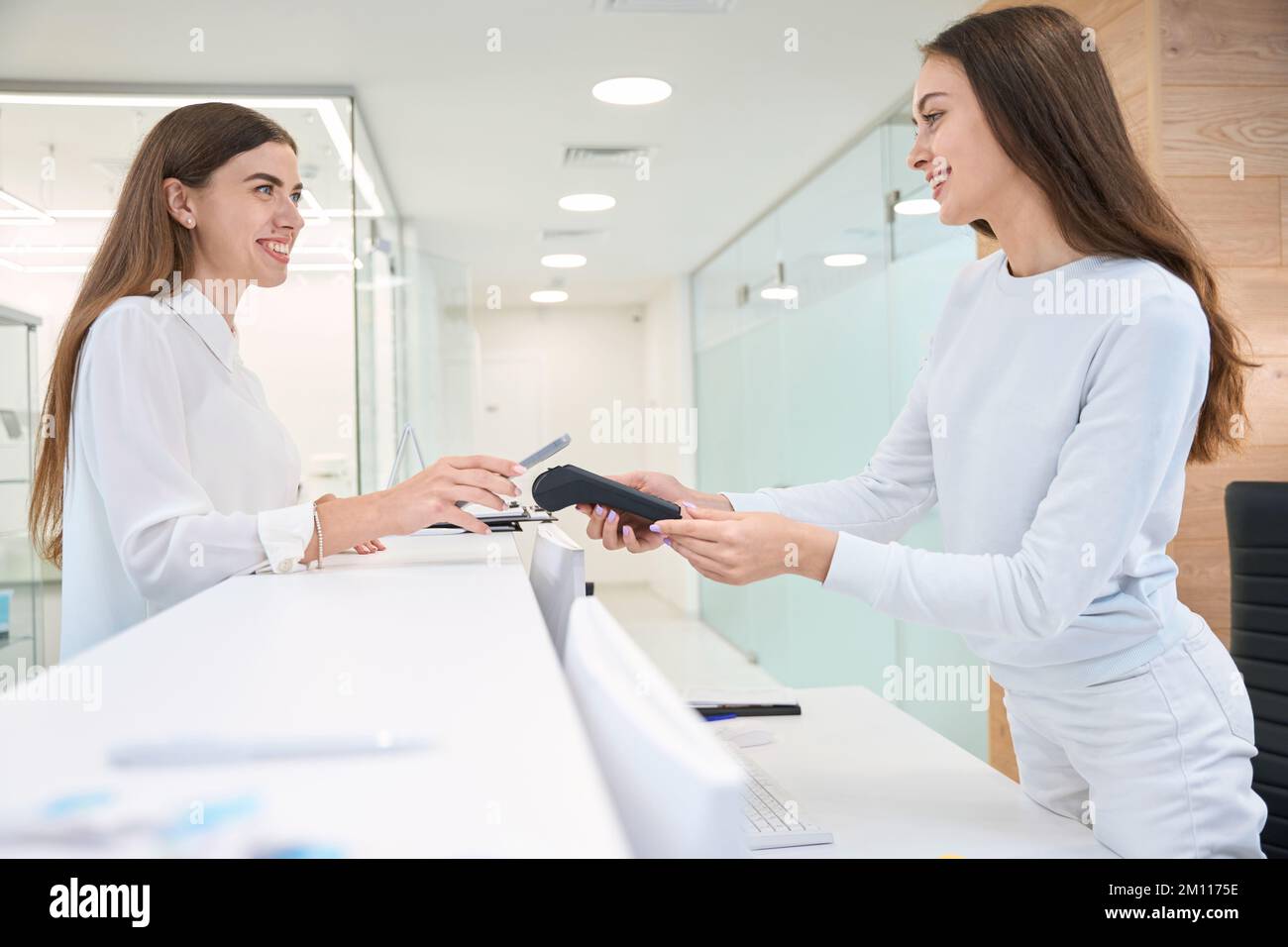 Pleased client paying with mobile device at reception counter Stock